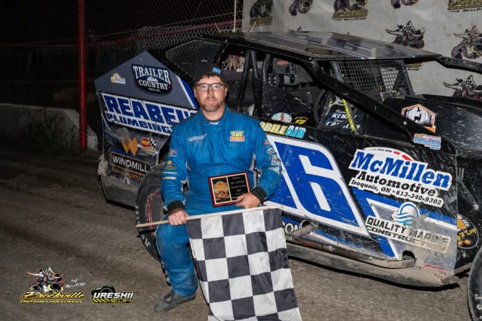 Man holding checkered flag by racecar