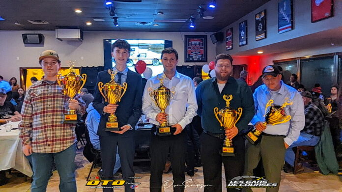 Men displaying racing trophies