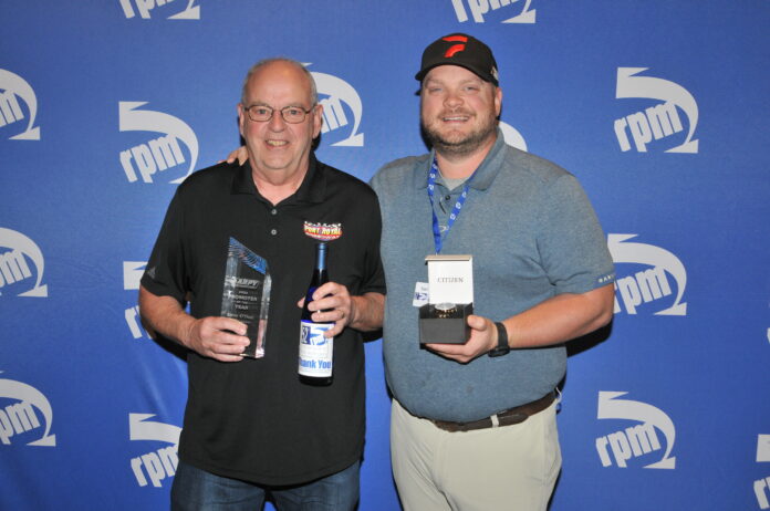 Two men displaying racing awards